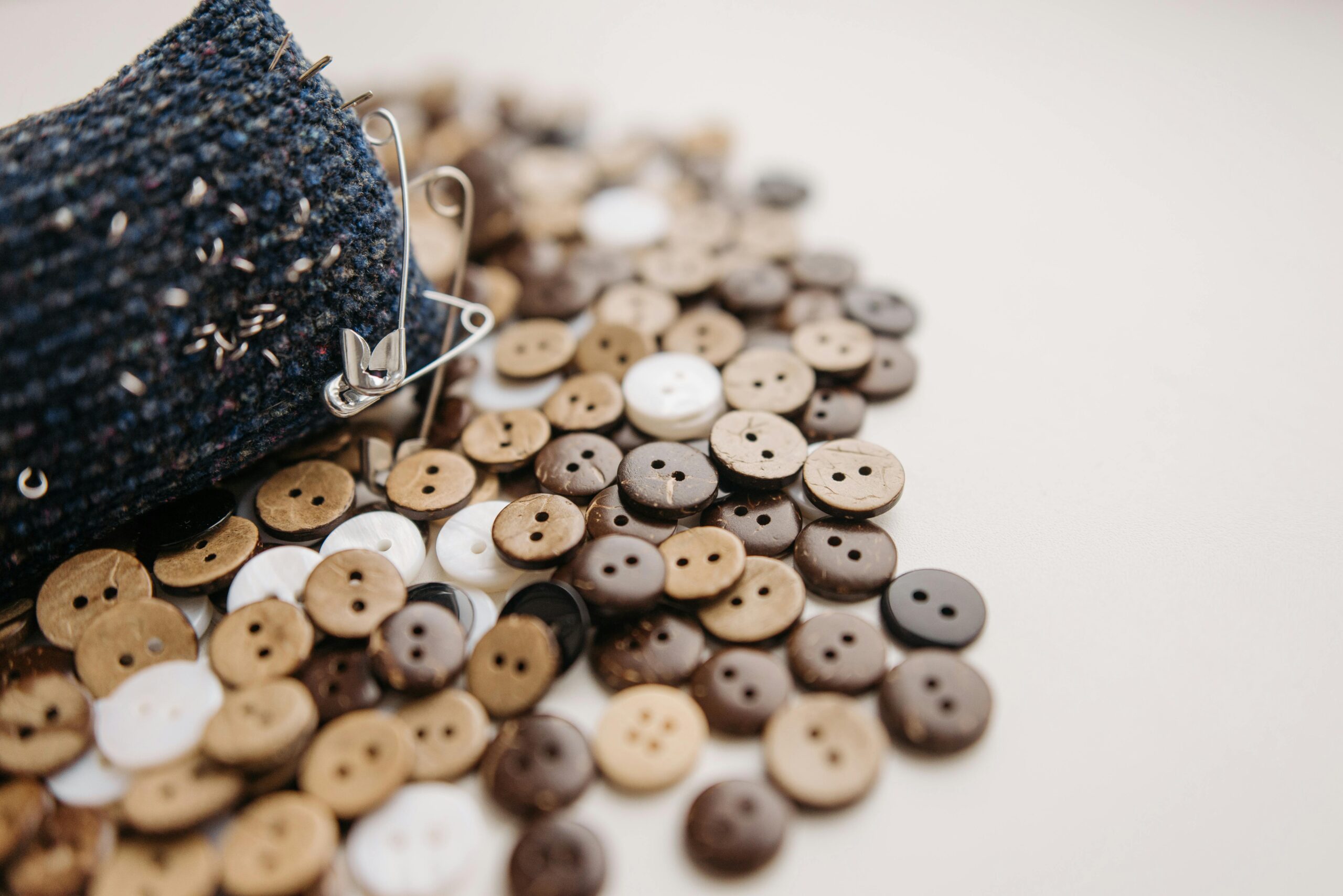 High-quality close-up of various wooden and plastic buttons with textured fabric and pin, perfect for DIY projects.