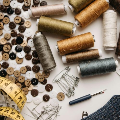 Colorful sewing threads, buttons, pins, and tools laid out for crafting.
